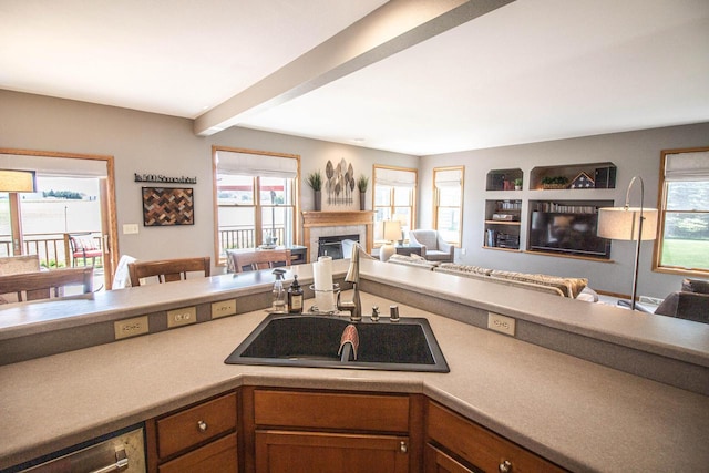 120 Wind Sail Ct, Random Lake, WI 53075 - kitchen featuring open floor plan, brown cabinets, a fireplace, beamed ceiling, and light countertops