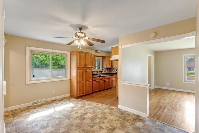 3918 W Hampton Ave, Milwaukee, WI 53209 - kitchen with a ceiling fan, brown cabinets, tasteful backsplash, stone finish flooring, and dark countertops