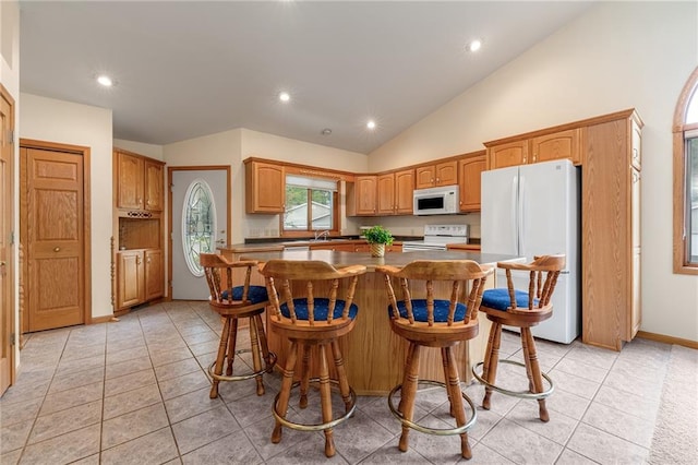 3413 Mcelroy Ct, Eau Claire, WI 54701 - kitchen featuring white appliances, a center island, light tile patterned floors, recessed lighting, and lofted ceiling