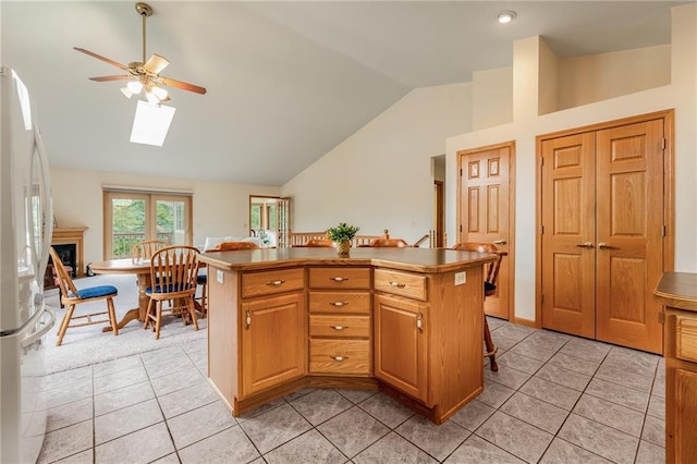 3413 Mcelroy Ct, Eau Claire, WI 54701 - kitchen featuring freestanding refrigerator, vaulted ceiling, ceiling fan, light tile patterned floors, and a skylight