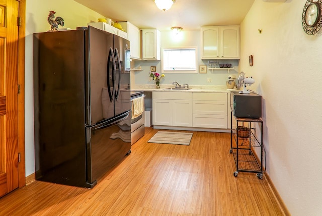 720 De Clark St, Beaver Dam, WI 53916 - kitchen with freestanding refrigerator, stainless steel range with electric stovetop, light wood finished floors, light countertops, and white cabinets