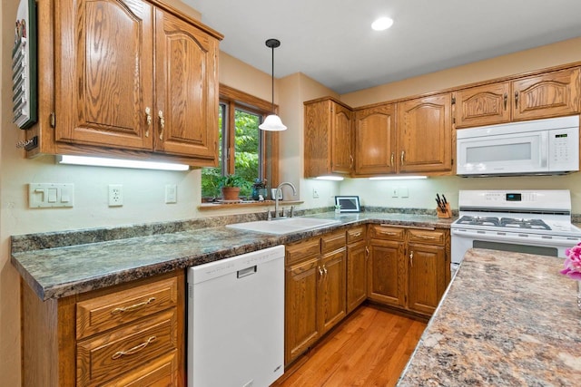 2510 Hillside Heights Dr, Green Bay, WI 54311 - kitchen with white appliances, brown cabinets, light wood-style floors, pendant lighting, and dark countertops