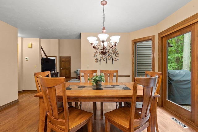 2510 Hillside Heights Dr, Green Bay, WI 54311 - dining space with a chandelier, light wood-type flooring, and stairway