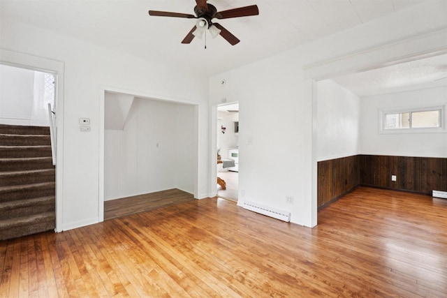 136 Oak St, Brillion, WI 54110 - empty room featuring wood-type flooring, a ceiling fan, stairs, baseboard heating, and wooden walls