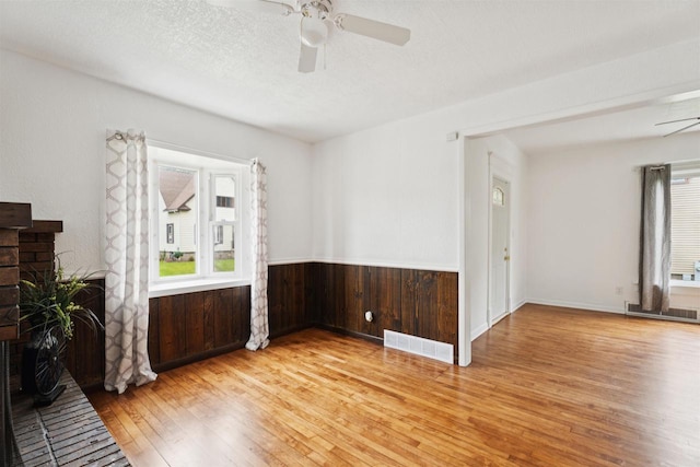 136 Oak St, Brillion, WI 54110 - unfurnished room featuring plenty of natural light, light wood-style floors, a ceiling fan, wainscoting, and wood walls