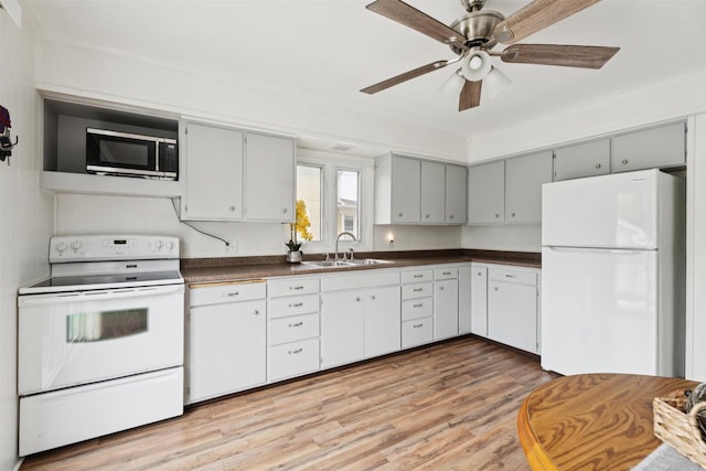 136 Oak St, Brillion, WI 54110 - kitchen featuring white appliances, dark countertops, light wood-style flooring, and ceiling fan