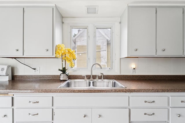 136 Oak St, Brillion, WI 54110 - kitchen with dark countertops, tasteful backsplash, and white cabinets