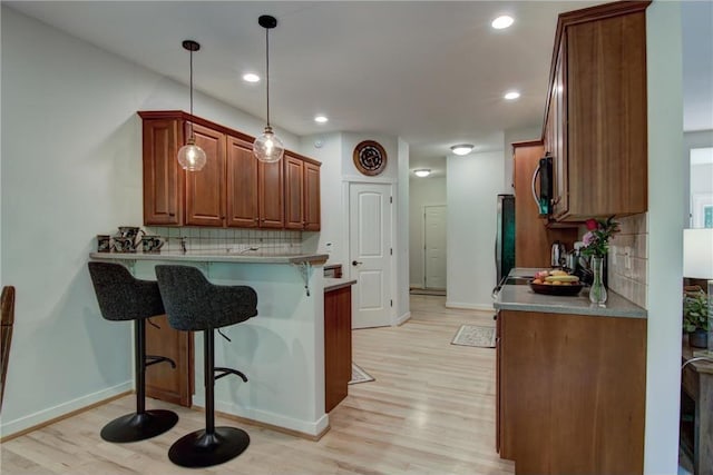1403 Elm Ave, Menomonie, WI 54751 - kitchen featuring a kitchen bar, light wood-style floors, backsplash, a peninsula, and recessed lighting