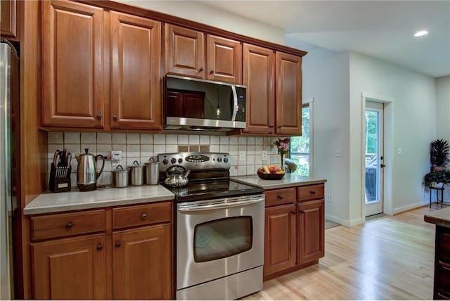 1403 Elm Ave, Menomonie, WI 54751 - kitchen with appliances with stainless steel finishes, decorative backsplash, light wood-style flooring, brown cabinetry, and recessed lighting