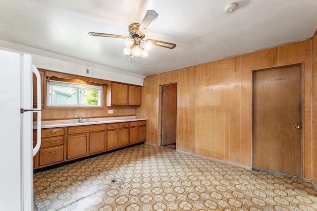 1647 Loomis St, La Crosse, WI 54603 - kitchen with freestanding refrigerator, brown cabinetry, light countertops, wood walls, and ceiling fan