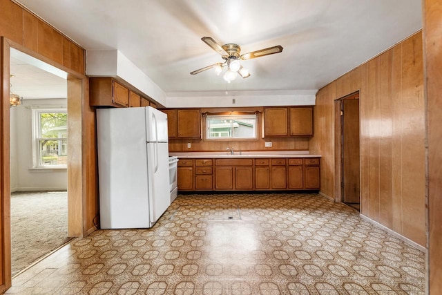 1647 Loomis St, La Crosse, WI 54603 - kitchen featuring white appliances, brown cabinetry, wooden walls, a ceiling fan, and light countertops