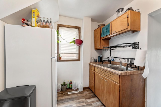 1432 Loomis St, La Crosse, WI 54603 - kitchen with freestanding refrigerator, light wood-type flooring, light countertops, and brown cabinets