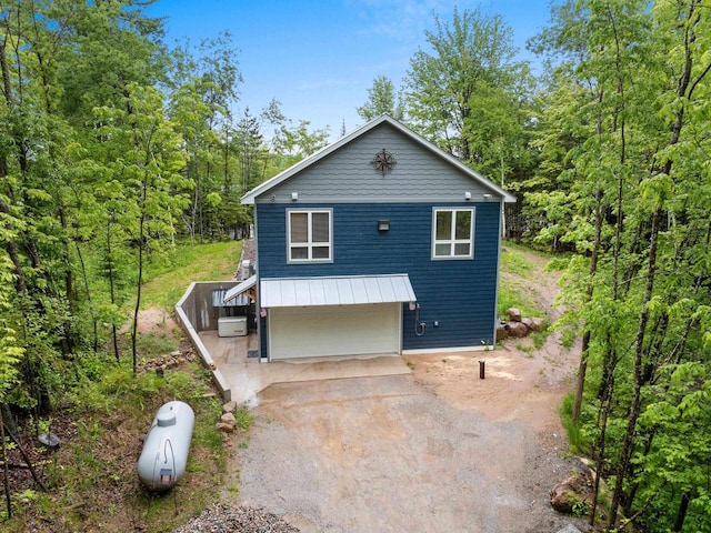 3838 Bear Lake Ln, Laona, WI 54541 - rustic home with dirt driveway, a garage, and a view of trees