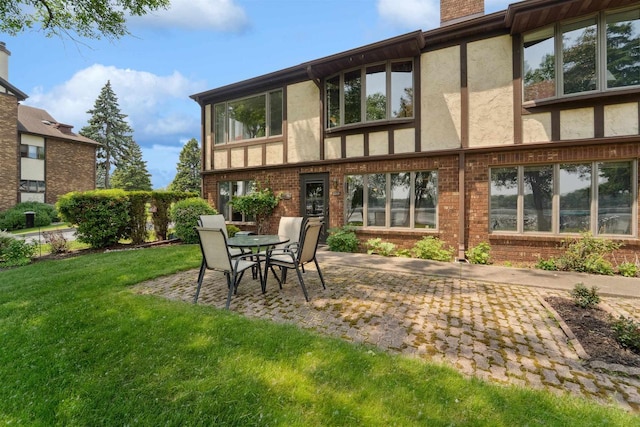 2213 Sunrise Dr, Appleton, WI 54914 - back of property featuring stucco siding, a patio, a yard, a chimney, and brick siding