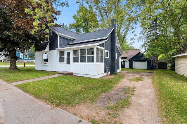 206 W Willow St, Bear Creek, WI 54922 - view of front of home featuring dirt driveway, a shingled roof, a garage, a front yard, and an outdoor structure