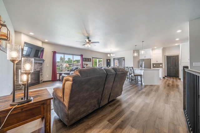 5090 N Milkweed Trl, Appleton, WI 54913 - living room with wood finished floors, a stone fireplace, a ceiling fan, recessed lighting, and a chandelier