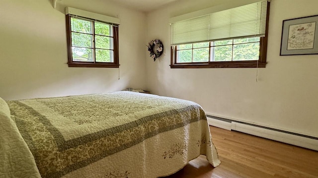 3218 N 13th St, Wausau, WI 54403 - bedroom featuring multiple windows, wood finished floors, and a baseboard heating unit