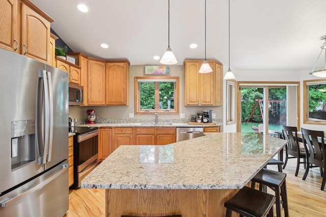 3176 Weybridge Dr, Sun Prairie, WI 53590 - kitchen with stainless steel appliances, light wood-style floors, a breakfast bar, light stone counters, and recessed lighting