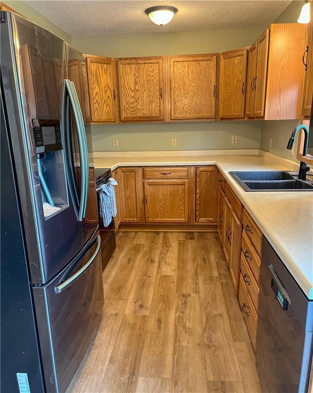 608 3rd St, Cameron, WI 54822 - kitchen with appliances with stainless steel finishes, light wood-type flooring, brown cabinetry, light countertops, and a textured ceiling