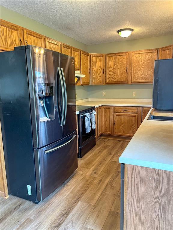 608 3rd St, Cameron, WI 54822 - kitchen featuring refrigerator with ice dispenser, range, light wood-style flooring, brown cabinets, and a textured ceiling