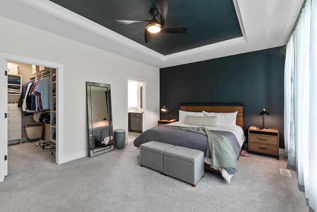 N55W19373 Red Crown Ln, Menomonee Falls, WI 53051 - bedroom featuring carpet flooring, a tray ceiling, a walk in closet, connected bathroom, and ceiling fan