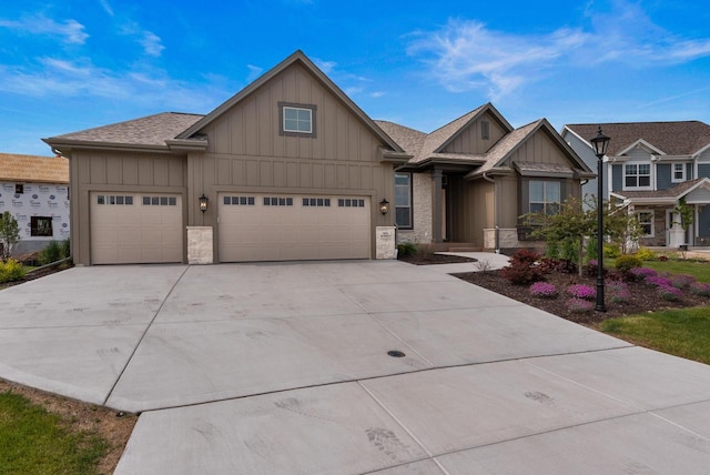 N55W19373 Red Crown Ln, Menomonee Falls, WI 53051 - view of front of home with board and batten siding, stone siding, concrete driveway, and an attached garage