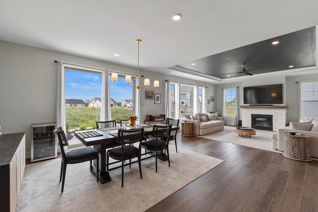 N55W19373 Red Crown Ln, Menomonee Falls, WI 53051 - dining space with beverage cooler, a tray ceiling, light wood-style floors, a fireplace, and a chandelier