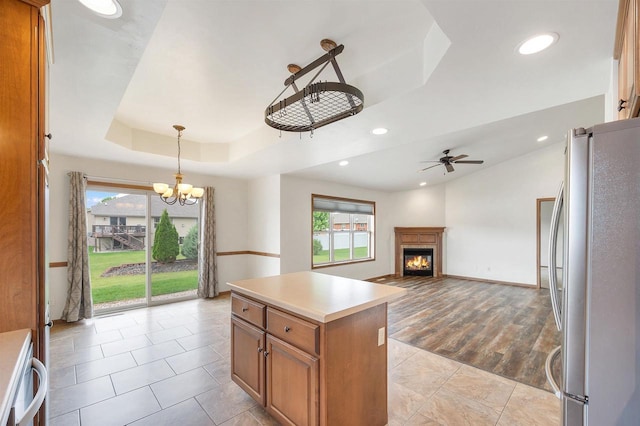 4815 Isabella Cir, Oneida, WI 54155 - kitchen featuring freestanding refrigerator, a raised ceiling, a ceiling fan, brown cabinetry, and a chandelier