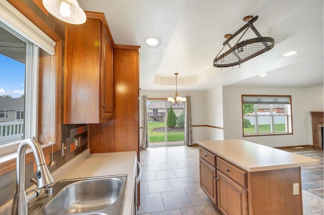 4815 Isabella Cir, Oneida, WI 54155 - kitchen featuring brown cabinets, a chandelier, light countertops, a kitchen island, and a tray ceiling