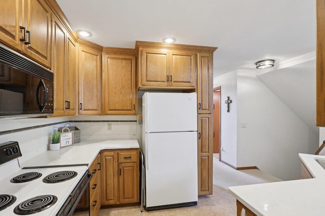 735 Cherokee Path, Lake Mills, WI 53551 - kitchen with freestanding refrigerator, electric stove, black microwave, light countertops, and light tile patterned floors