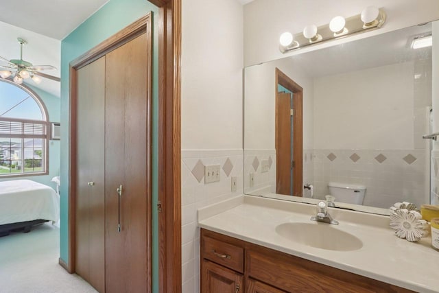 735 Cherokee Path, Lake Mills, WI 53551 - ensuite bathroom with tile walls, vanity, ceiling fan, and wainscoting