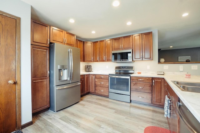 215 Marcoe St, Fond Du Lac, WI 54937 - kitchen with stainless steel appliances, brown cabinetry, light wood-type flooring, light countertops, and recessed lighting