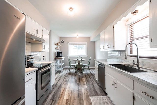 10610 W Rogers St, West Allis, WI 53227 - kitchen featuring appliances with stainless steel finishes, under cabinet range hood, decorative backsplash, dark wood-style flooring, and white cabinetry