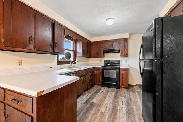 1517 Navarino St, Algoma, WI 54201 - kitchen with black appliances, under cabinet range hood, light wood-style floors, and light countertops