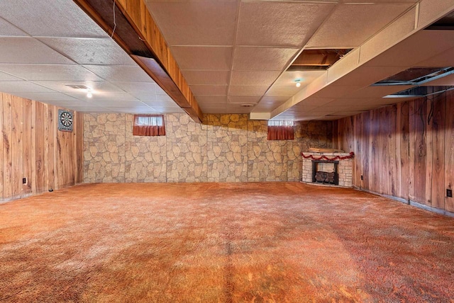 1517 Navarino St, Algoma, WI 54201 - basement featuring a drop ceiling, wooden walls, carpet, and a brick fireplace