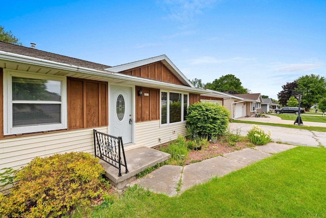 1517 Navarino St, Algoma, WI 54201 - view of front of property with board and batten siding, concrete driveway, a front yard, and a garage