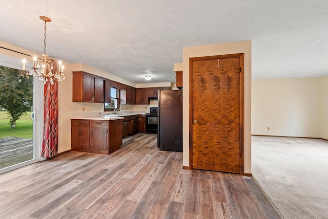 1517 Navarino St, Algoma, WI 54201 - kitchen featuring black appliances, light countertops, a chandelier, light wood-style flooring, and decorative light fixtures