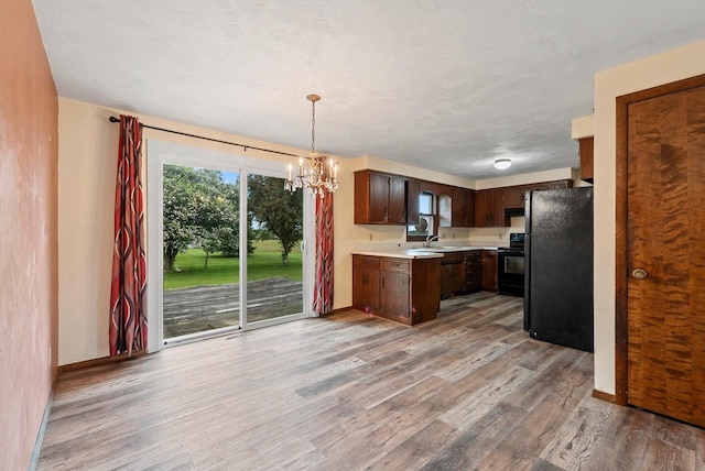 1517 Navarino St, Algoma, WI 54201 - kitchen with black appliances, light countertops, light wood-style floors, a chandelier, and dark brown cabinetry