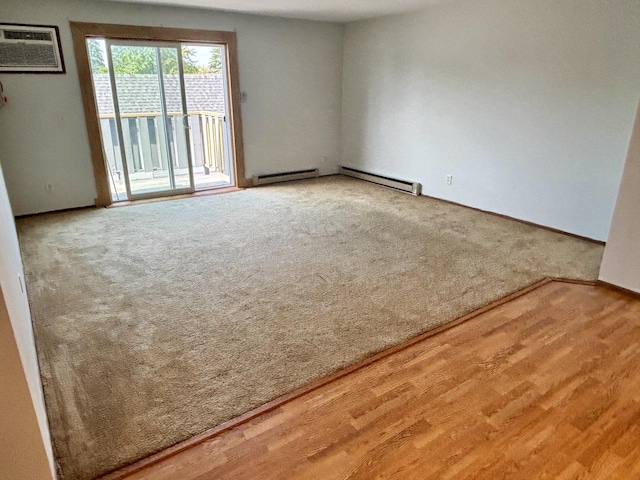 1712 Creek Rd Unit 202, West Bend, WI 53090 - carpeted spare room with baseboard heating, a wall unit AC, a baseboard radiator, and wood finished floors