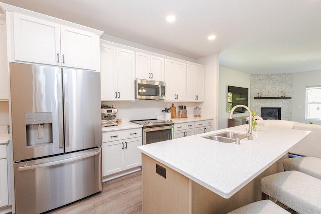 310 Paradise Ct, Hartland, WI 53029 - kitchen featuring appliances with stainless steel finishes, light wood-style flooring, a kitchen breakfast bar, open floor plan, and white cabinetry