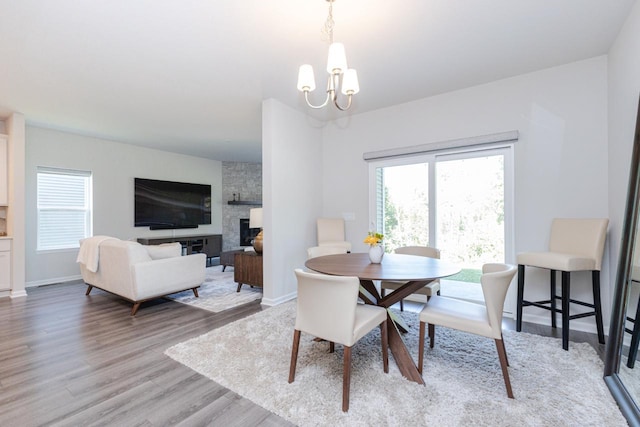 310 Paradise Ct, Hartland, WI 53029 - dining space with a chandelier, healthy amount of natural light, light wood-style floors, and a fireplace