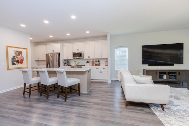 310 Paradise Ct, Hartland, WI 53029 - kitchen featuring stainless steel appliances, a center island with sink, white cabinets, light countertops, and a kitchen breakfast bar
