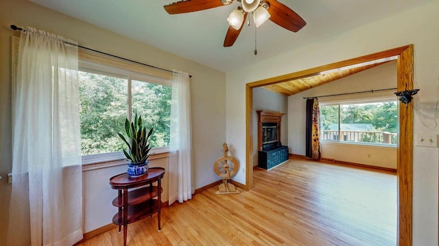 N2493 Kunz Rd, Fort Atkinson, WI 53538 - unfurnished room with vaulted ceiling, light wood-style flooring, a glass covered fireplace, and ceiling fan
