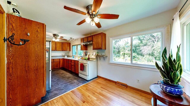N2493 Kunz Rd, Fort Atkinson, WI 53538 - kitchen with white gas range oven, under cabinet range hood, brown cabinetry, light countertops, and a ceiling fan