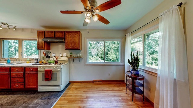 N2493 Kunz Rd, Fort Atkinson, WI 53538 - kitchen featuring white gas range, under cabinet range hood, ceiling fan, dark wood-style floors, and light countertops