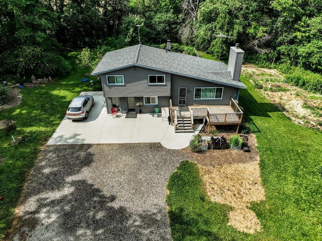 N2493 Kunz Rd, Fort Atkinson, WI 53538 - rear view of house with a chimney, a lawn, a view of trees, and a deck