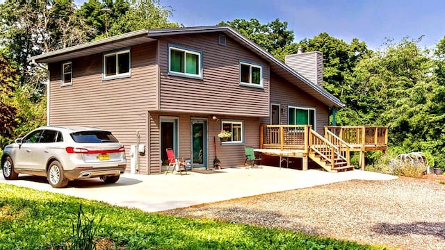 N2493 Kunz Rd, Fort Atkinson, WI 53538 - view of front of house with a chimney, a wooden deck, concrete driveway, and a patio area