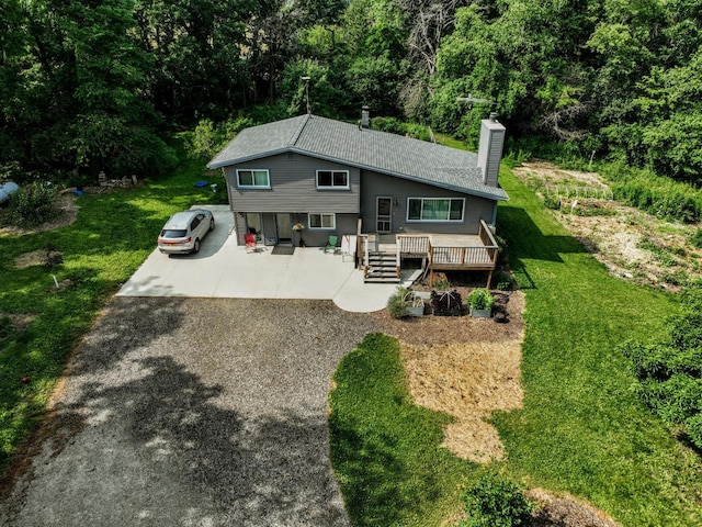 N2493 Kunz Rd, Fort Atkinson, WI 53538 - view of front of house featuring a chimney, a front lawn, a wooden deck, and a wooded view