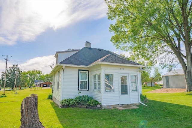 500 2nd Ave, Hollandale, WI 53544 - view of property exterior featuring a chimney, a yard, and a shingled roof