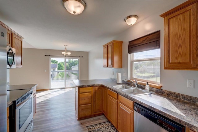 862 Stonefield Dr, Edgerton, WI 53534 - kitchen featuring appliances with stainless steel finishes, light wood-style flooring, a peninsula, a chandelier, and dark countertops